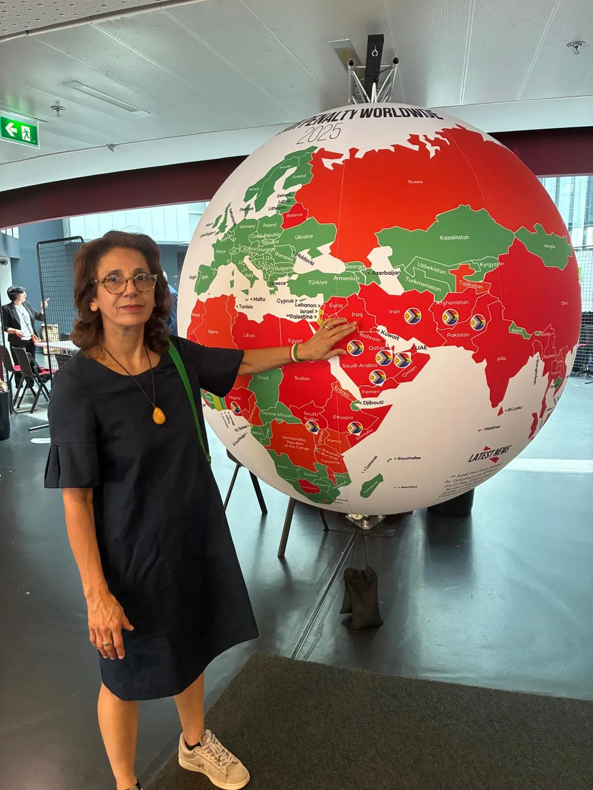 Noushin Mirjalili standing beside a world map installation at a human-rights congress